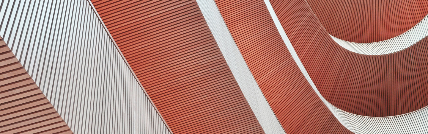 Abstraktes architektonisches Detail mit geschwungenen terrakottafarbenen Oberflächen mit geometrischen Linienmustern und weißen Strukturelementen