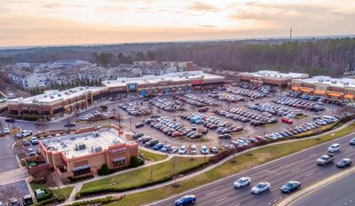 Aerial view of a shopping center at sunset, showcasing vibrant colors and the layout of stores and parking areas.