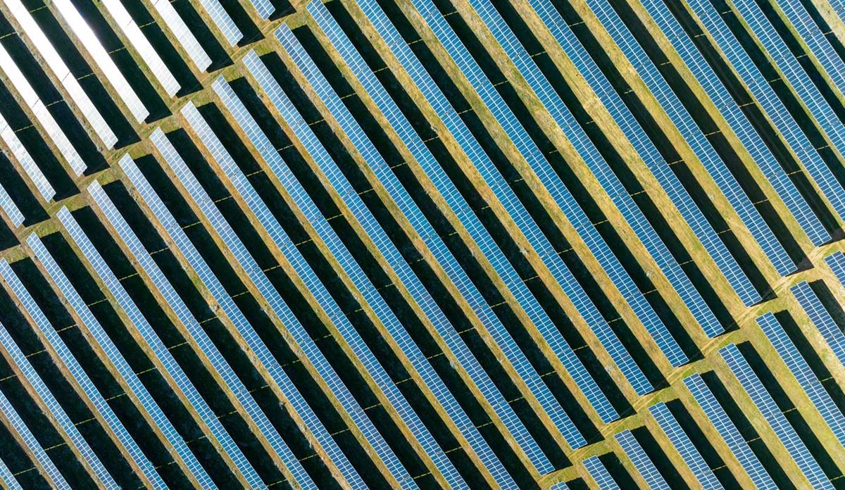 Aerial view of neatly arranged rows of solar panels installed on open land