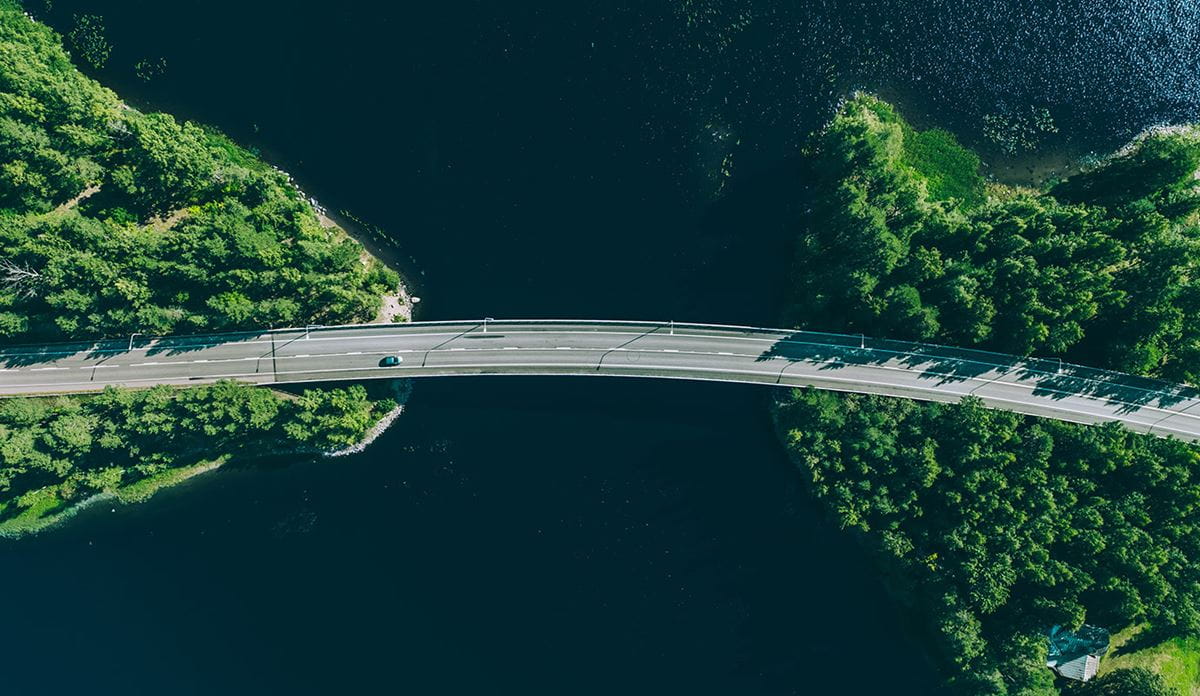 Bridge over water with surrounding greenery, aerial view