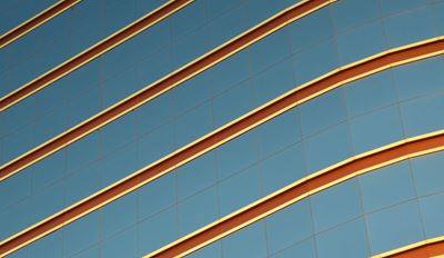 Abstract architectural pattern with diagonal metallic lines across a blue glass