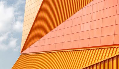 A bright orange building is set against a backdrop of a clear blue sky, highlighting its vivid color.