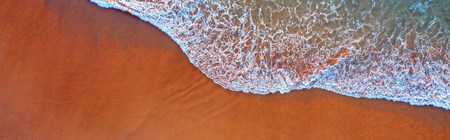 orange sand with white sea waves at shore
