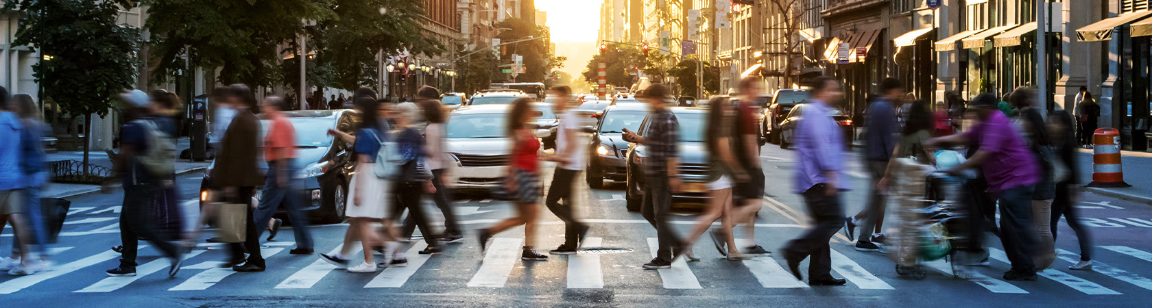 A crowded cross walk in a city at sunset