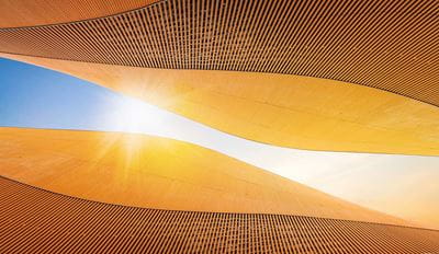 Modern architectural curves with wooden slat details against blue sky