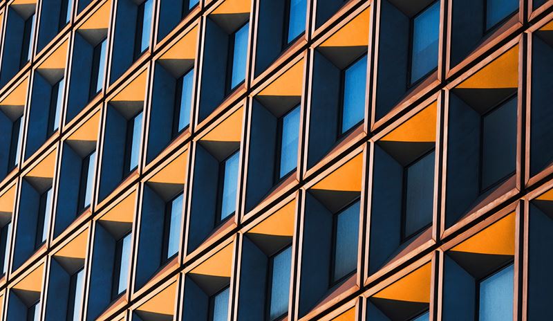 Modern building facade featuring repeating geometric windows patterns in blue and yellow tones