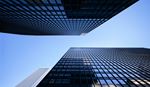 Low-angle view of modern glass skyscrapers against a clear blue sky.