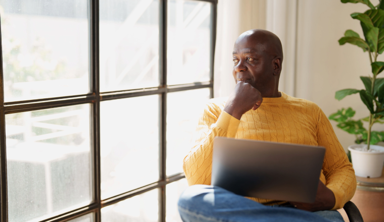 Man with laptop watching outside the window