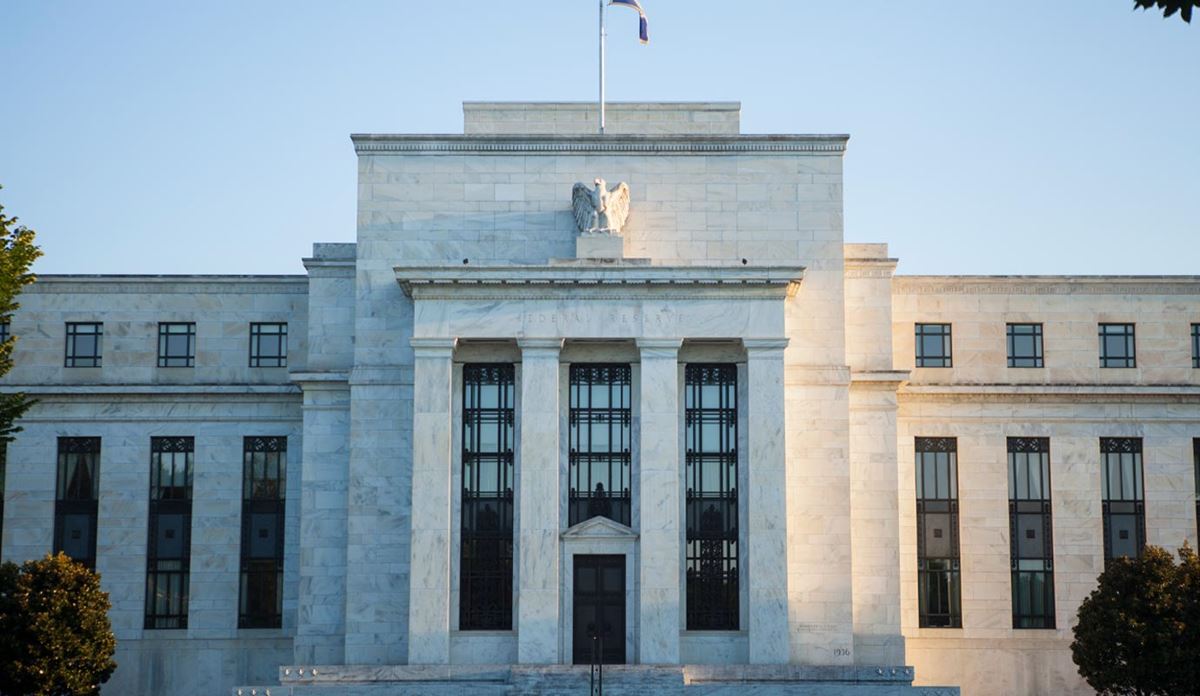 The Federal Reserve Building in Washington, D.C., with neoclassical architecture and American flag.