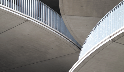 Curved concrete walkways with white railings and geometric patterns