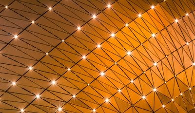 Abstract geometric pattern of glowing nodes connected by lines on a golden background.