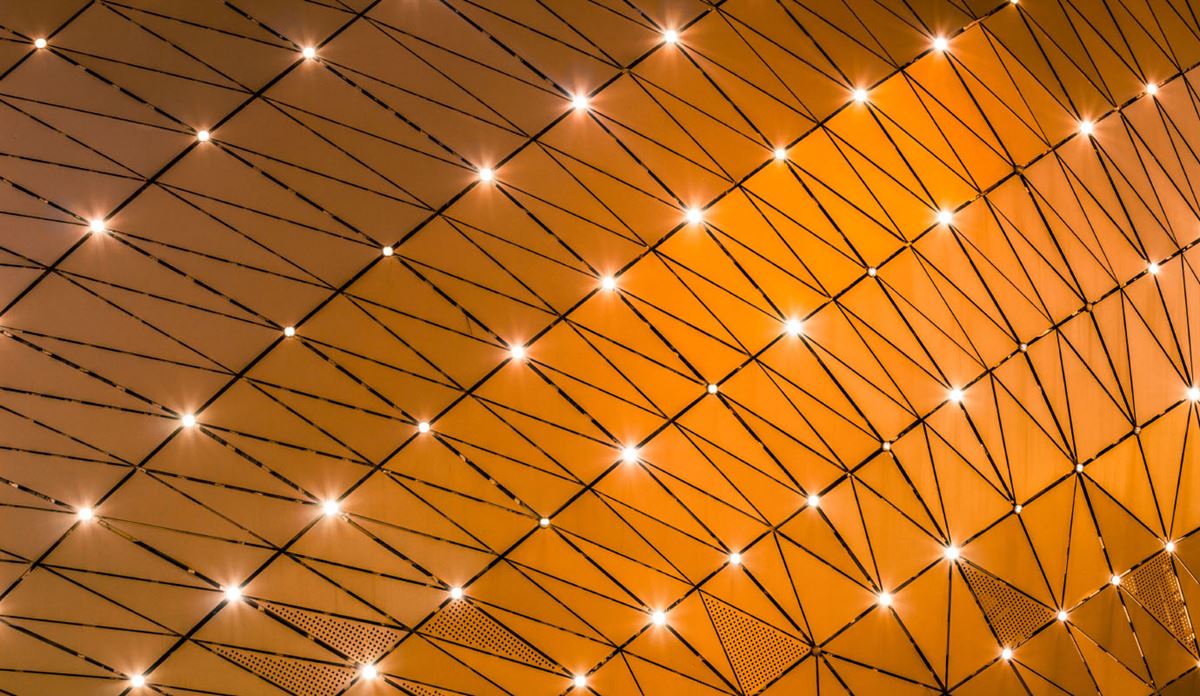 Abstract geometric pattern of glowing nodes connected by lines on a golden background.