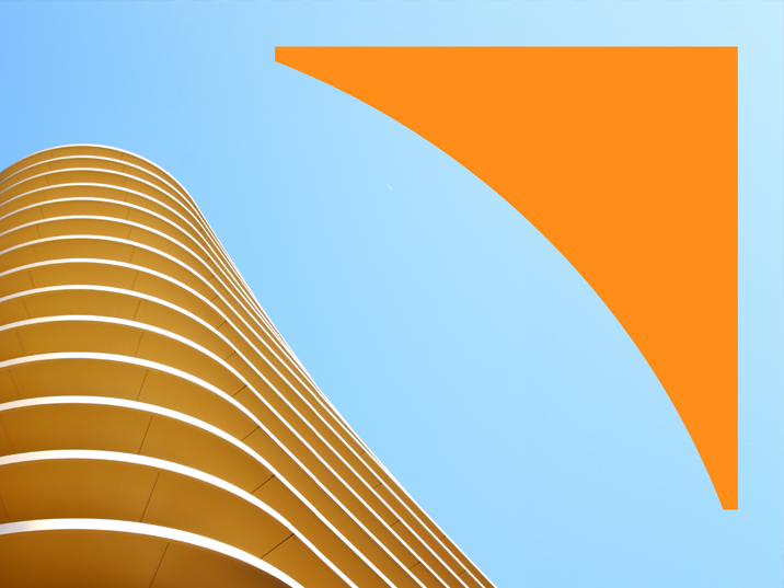 Looking up at a curved modern building with an orange facade against a blue sky, with an orange geometric shape in the upper right corner.