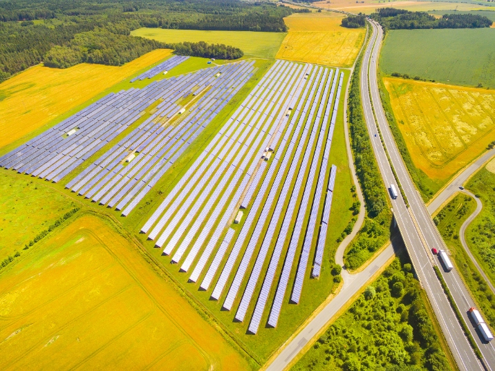 Aerial view of solar panels across farmland beside a highway