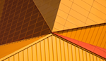 Abstract close-up of angular modern building facade in warm gold, orange, and red tones