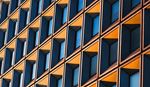 Modern building facade featuring repeating geometric windows patterns in blue and yellow tones