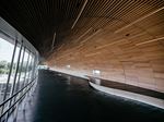 Curved wooden ceiling and walkway along a glass window terminal.