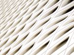 Close-up view of a modern white architectural facade with a repeating pattern of curved, eye-shaped openings arranged in diagonal row.