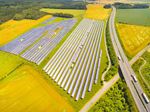 Aerial view of solar panels across farmland beside a highway