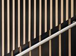Metal handrail against a striped wood-slat wall.