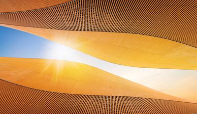 Modern architectural curves with wooden slat details against blue sky