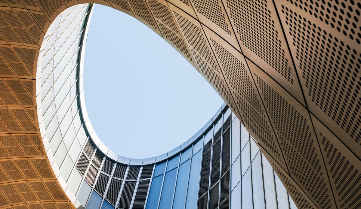 View from inside a building, looking up at a clear blue sky framed by the structure's edges
