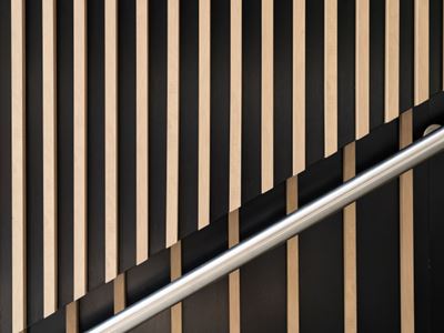 Metal handrail against a striped wood-slat wall.