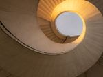 A spiral staircase illuminated by light streaming through, creating a warm and inviting atmosphere.