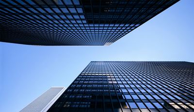 Low-angle view of modern glass skyscrapers against a clear blue sky.