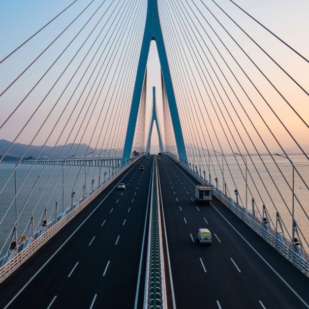 Aerial view of a cable-stayed suspension bridge spanning water at dusk, symbolizing long-term infrastructure investment