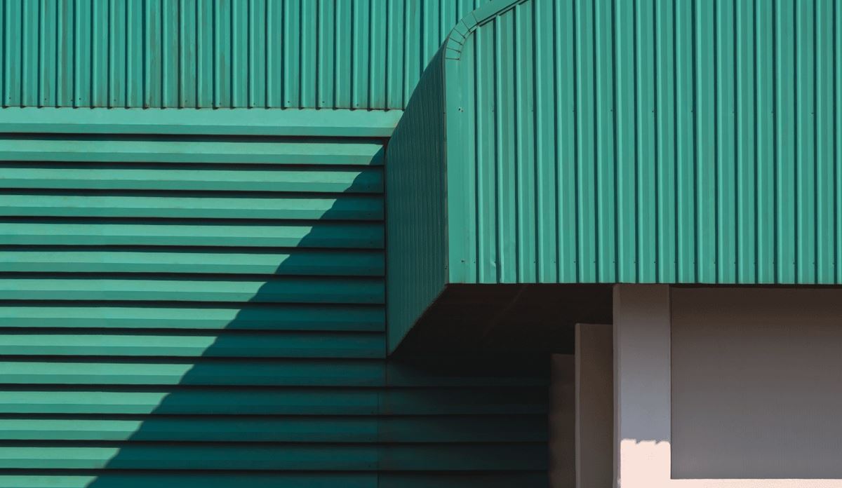 A green building featuring a white roof and green siding, set against a clear sky.