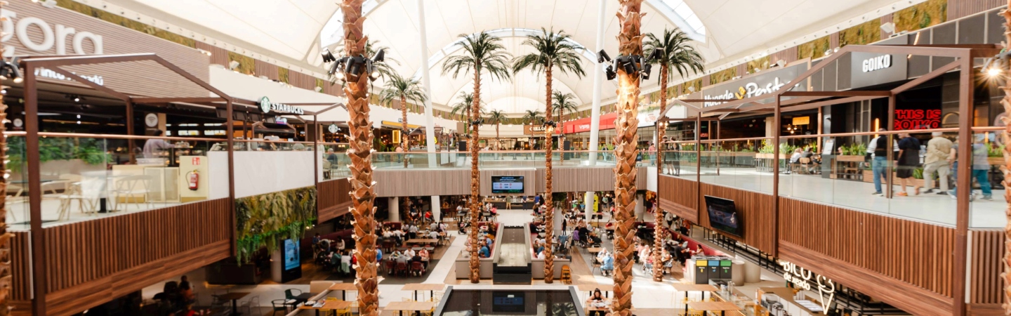 Bright indoor shopping mall with trees and walkways