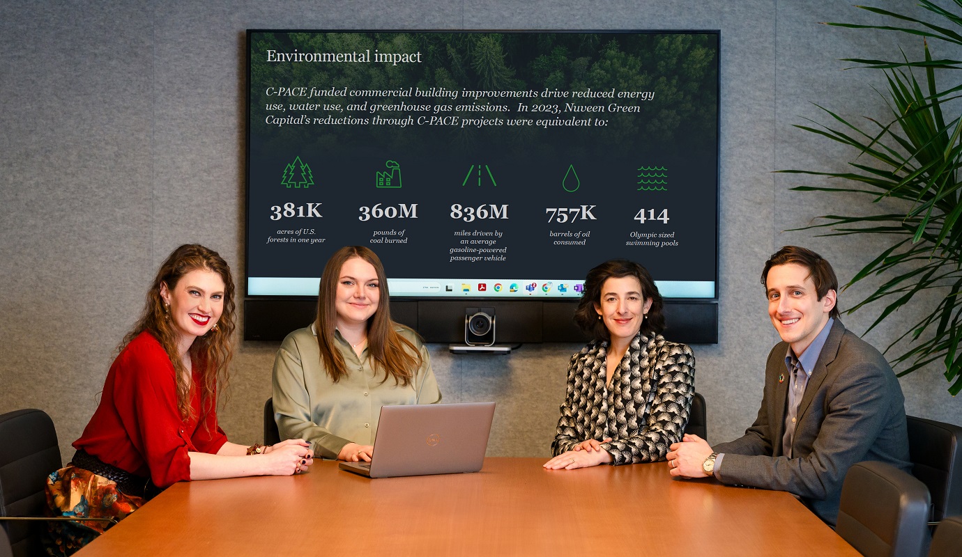 Four people smiling while sitting at a conference table