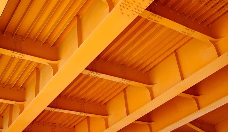 Vista della parte inferiore di un ponte che mostra diverse travi arancioni