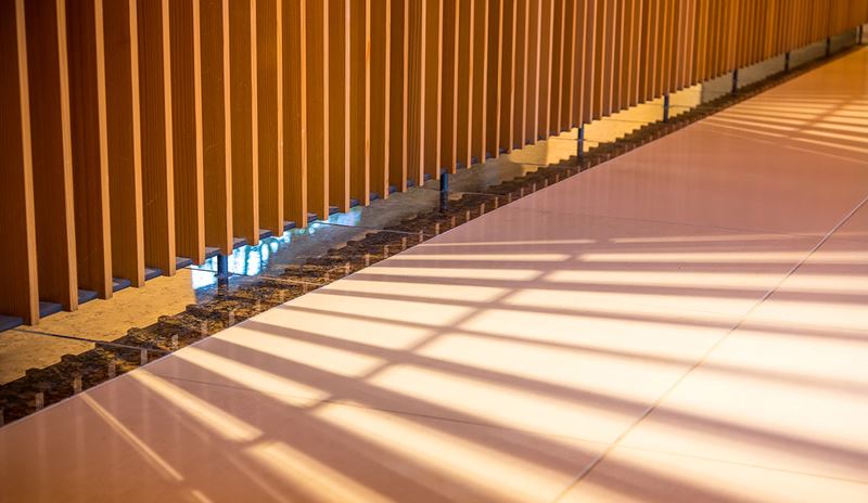 Un lungo corridore che presenta una parete di legno illuminata da una luce brillante, creando un'atmosfera calda e accogliente.