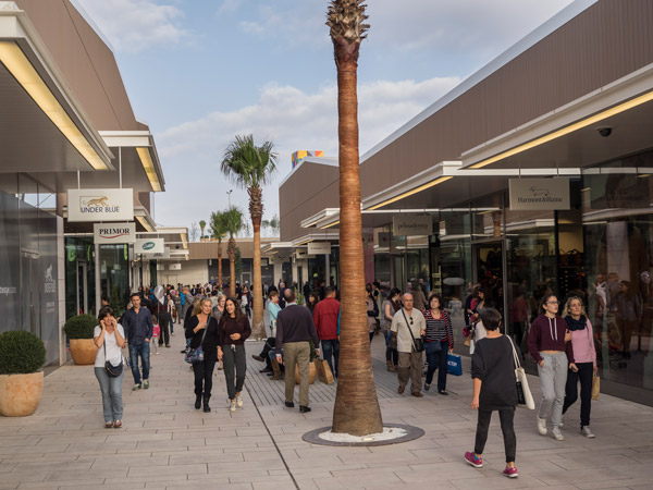 Clienti che passano davanti alle palme dell'outlet di Viladecans
