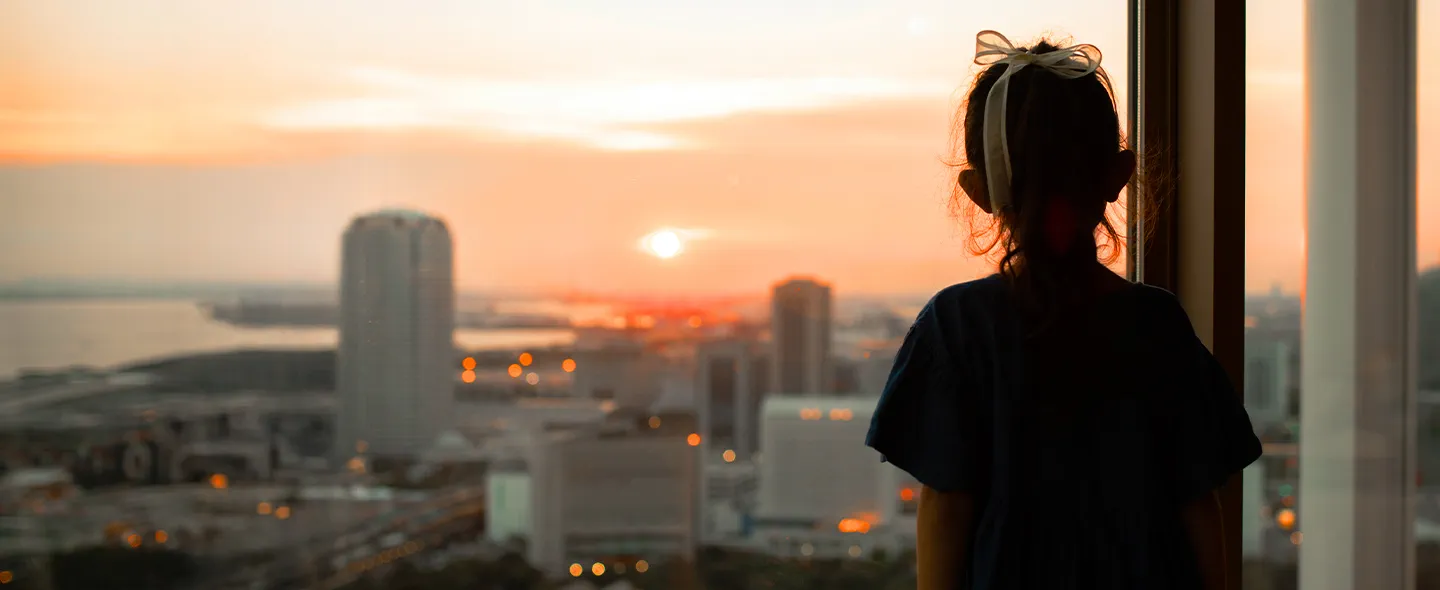 少女が窓の外を眺めながら、夕焼けの鮮やかな色を賞賛している。